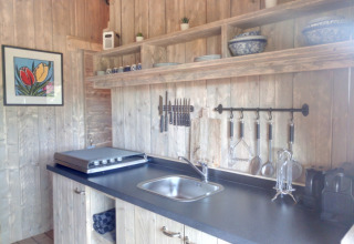 Køkkenområde i Casa da Vinha - Glamping Lodges i Alentejo med trævægge, hylder og håndlavet dekoration.