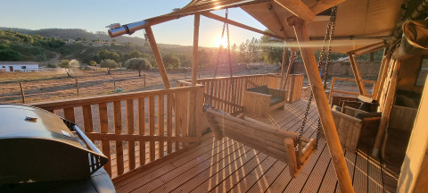 Houten terras met schommels en barbecue bij Casa da Vinha - Glamping Lodges in Alentejo bij zonsondergang.