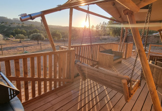 Houten terras met schommels en barbecue bij Casa da Vinha - Glamping Lodges in Alentejo bij zonsondergang.