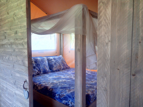 Alojamiento glamping acogedor con puerta de madera y cama con dosel en Casa da Vinha - Glamping Lodges, Alentejo.