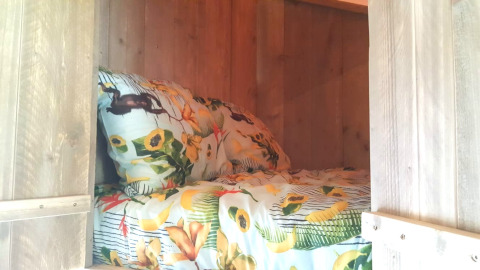 Letto accogliente con biancheria floreale in una glamping lodge di legno a Casa da Vinha, Alentejo.