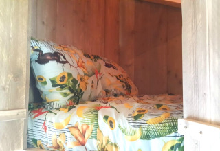 Knus bed met bloemig beddengoed in een houten glamping lodge bij Casa da Vinha in Alentejo, Portugal.