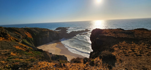 Zicht op het strand en de kliffen bij Casa da Vinha - Glamping Lodges in Alentejo tijdens zonsondergang.