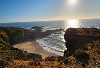 Zicht op het strand en de kliffen bij Casa da Vinha - Glamping Lodges in Alentejo tijdens zonsondergang.