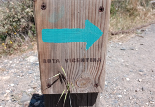Cartel de madera con flecha azul y 'Rota Vicentina', junto a la ruta y al glamping Casa da Vinha en Alentejo.