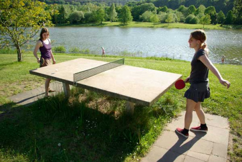 Due ragazze giocano a ping pong all'aperto vicino al lago al Camping Axelsee - Blokhutten Noordrijn-Westfalen.