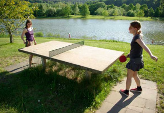 Dos chicas juegan al tenis de mesa al aire libre junto al lago en Camping Axelsee - Blokhutten Noordrijn-Westfalen.
