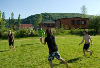 Giovani giocano a palla sull'erba davanti alle cabine di Camping Axelsee, Renania Settentrionale-Vestfalia.