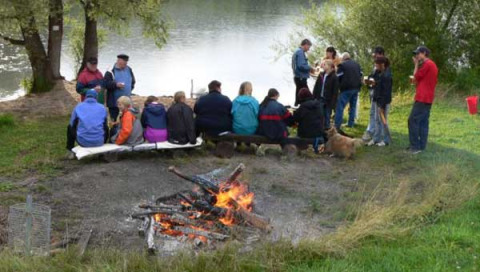 Gruppe verbringt Zeit am Lagerfeuer am Seeufer im Camping Axelsee - Blokhutten Nordrhein-Westfalen.