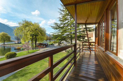 Vue depuis le balcon du Campofelice Village Camping - Chalet Lago Maggiore sur le lac, arbres et montagnes.