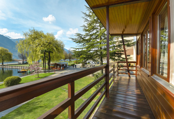 Vista dal balcone di Campofelice Village Camping - Chalet Lago Maggiore con lago, alberi e montagne.