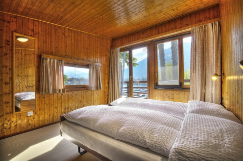 Camera da letto in legno presso Campofelice Village Camping - Chalet Lago Maggiore con grandi finestre panoramiche.