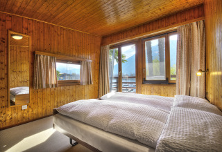 Camera da letto in legno presso Campofelice Village Camping - Chalet Lago Maggiore con grandi finestre panoramiche.