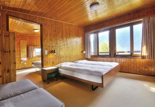 Indvendigt billede af et lyst træbeklædt soveværelse i Campofelice Village Camping - Chalet Lago Maggiore.