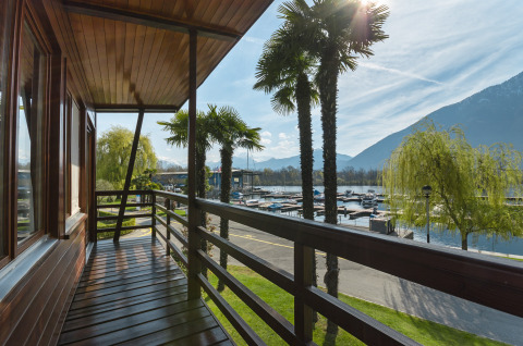 Vista da un balcone di legno con palme al Campofelice Village Camping - Chalet Lago Maggiore, Svizzera.