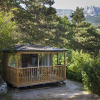 A cozy wooden glamping cabin surrounded by trees at Huttopia Gorges du Verdon, glamping Alpes-de-Haute-Provence.