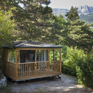 Knusse houten glampingaccommodatie tussen bomen bij Huttopia Gorges du Verdon, glamping Alpes-de-Haute-Provence.