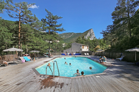 Outdoor swimming pool with wooden deck at Huttopia Gorges du Verdon glamping in Alpes-de-Haute-Provence.