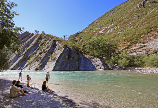Familie nyder naturen ved en flod med bjerge og skrånende klippeformationer på Huttopia Gorges du Verdon.