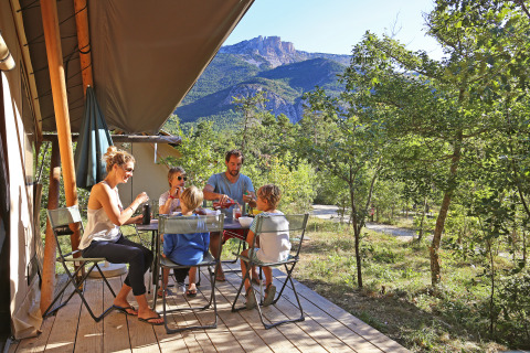 Gezin ontbijt op het terras van een glampingtent bij Huttopia Gorges du Verdon, Alpes-de-Haute-Provence.