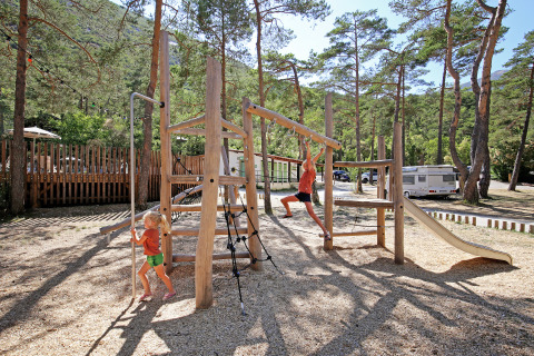 Børn leger på legeplads i skovklædt område ved Huttopia Gorges du Verdon glamping i Alpes-de-Haute-Provence.