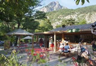 Outdoor café area at Huttopia Gorges du Verdon glamping, surrounded by mountains and trees in Alpes-de-Haute-Provence.