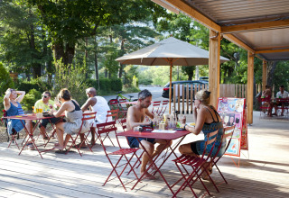 Udendørs spisende gæster på Huttopia Gorges du Verdon glamping i Alpes-de-Haute-Provence på en solrig dag.