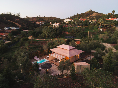 Lodge Lua glamping-accommodatie met zwembad in Algarve, Portugal, omringd door heuvels en groen.