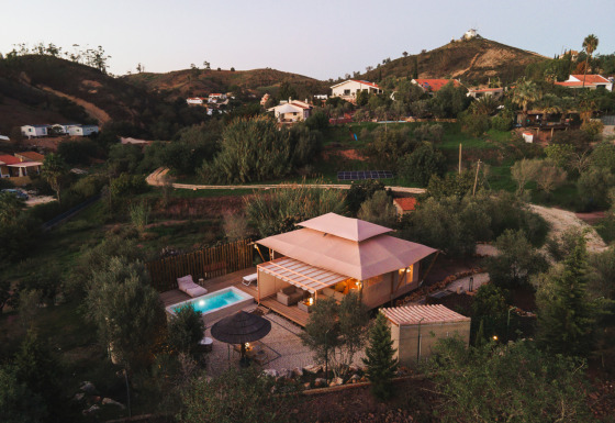 Lodge Lua glamping-accommodatie met zwembad in Algarve, Portugal, omringd door heuvels en groen.