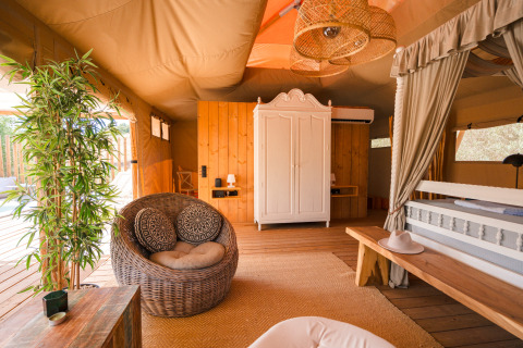 Interior de la Lodge Lua en Portugalvillas - Glamping Algarve, tienda de lujo con muebles de mimbre y madera.