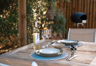 Udendørs borddækning med vin og tallerkener ved Lodge Lua, Portugalvillas Glamping Algarve i naturen.