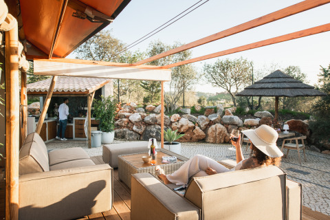 Kvinde slapper af i glamping-indkvartering Lodge Lua i Algarve, Portugal, omgivet af natur og komfort.