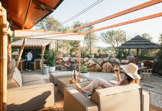 Vrouw ontspant bij Lodge Lua - Glamping Algarve in Portugal, buiten zittend met wijn in een natuurlijke omgeving.
