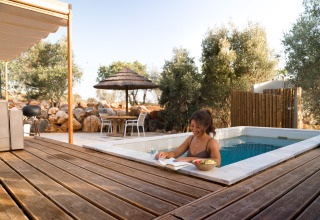 Vrouw ontspant bij Lodge Lua - Portugalvillas Glamping Algarve, lezend bij het zwembad met fruit op het zonnige dek.
