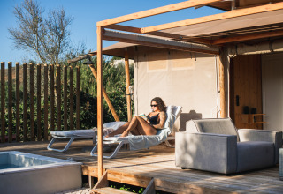 Kvinde slapper af på Lodge Lua, Portugalvillas Glamping Algarve, solrig terrasse med pool og natur.