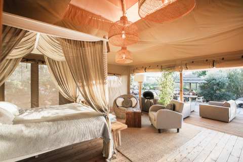Alojamiento glamping de lujo con cama con dosel y zona lounge en Lodge Lua, Algarve, Portugal.