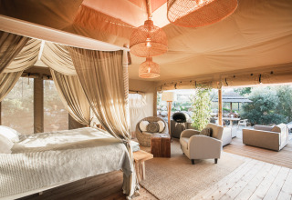 Alojamiento glamping de lujo con cama con dosel y zona lounge en Lodge Lua, Algarve, Portugal.