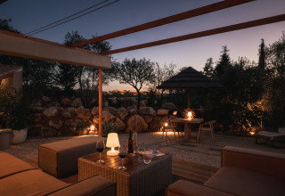 Zona lounge exterior en Lodge Lua - Portugalvillas - Glamping Algarve iluminada suavemente al anochecer.