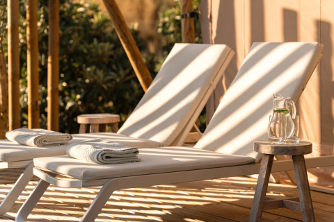Comfortabele ligstoelen met handdoeken en waterkan op houten tafel bij Lodge Lua - Portugalvillas Glamping Algarve.