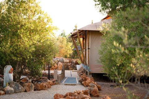 Lodge Lua glamping indkvartering i Algarve, Portugal, omgivet af grønne træer og natursten.