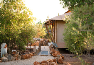 Lodge Lua glamping indkvartering i Algarve, Portugal, omgivet af grønne træer og natursten.