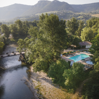 Luftaufnahme von Huttopia Millau - Glamping Aveyron mit Pool, Fluss und grüner Landschaft im Hintergrund.