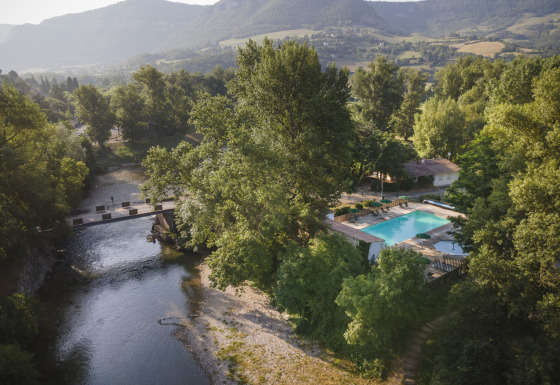 Luftfoto af Huttopia Millau - Glamping Aveyron, med swimmingpool omgivet af træer og bjerglandskab.