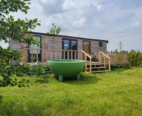 Alloggio glamping presso Stadslandgoed De Heicohoeve a Gelderland, Paesi Bassi, con casetta e vasca esterna verde.