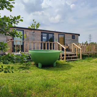 Glampingverblijf op Stadslandgoed De Heicohoeve in Gelderland met pipowagen en grote groene buitentobbe.