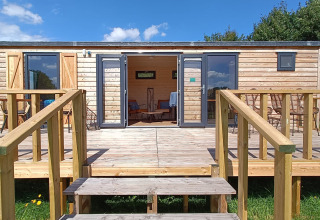 Udendørs udsigt af en træhytte med terrasse på Stadslandgoed De Heicohoeve - Pipowagens Gelderland.