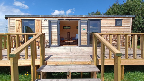 Buitenaanzicht van een houten hut met terras bij Stadslandgoed De Heicohoeve - Pipowagens Gelderland.