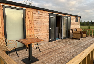 Wooden deck with chairs at glamping site Stadslandgoed De Heicohoeve - Pipowagens Gelderland, relaxing outdoor area.