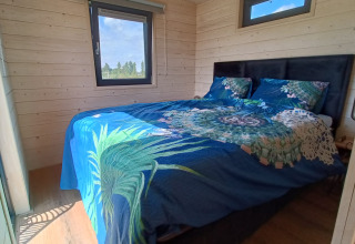 Habitación en alojamiento glamping en Stadslandgoed De Heicohoeve - Pipowagens Gelderland, con ropa de cama azul.