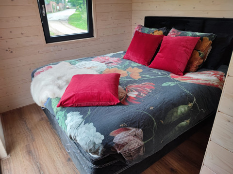 Komfortabel seng i glampingindkvartering på Stadslandgoed De Heicohoeve Pipowagens Gelderland med farverige puder.